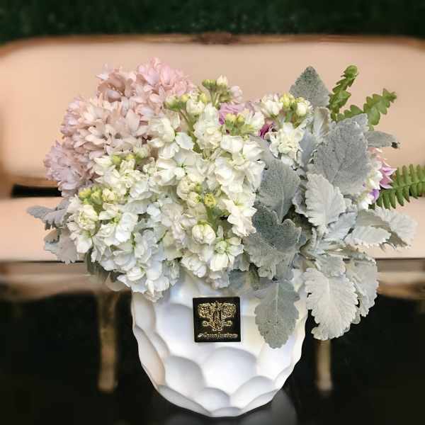 White and pale pink flowers in a white vase with silver foliage