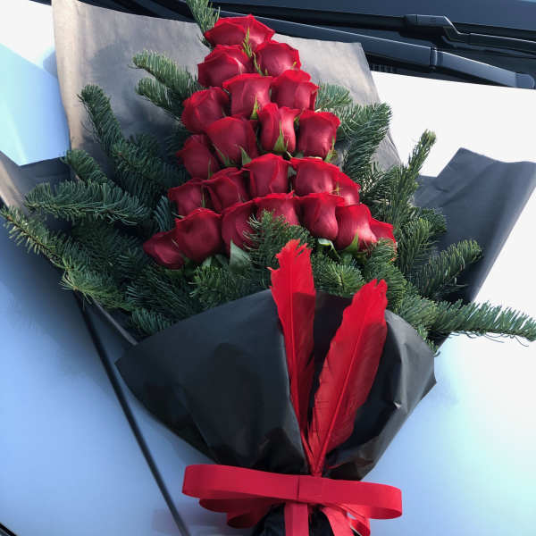 Bouquet of red roses wrapped in black paper with a red ribbon