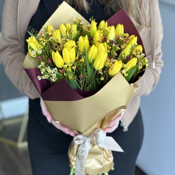 Bouquet of yellow tulips wrapped in gold and burgundy paper