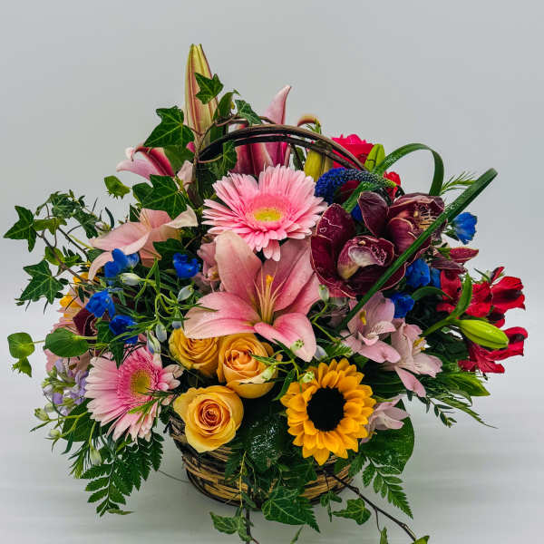 Mixed flower basket with pink lilies, roses, and sunflowers