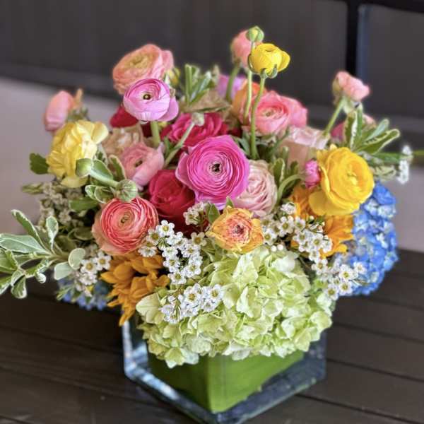 Colorful mixed bouquet in a square glass vase with hydrangea and ranunculus
