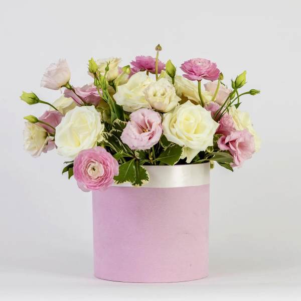 Pink and white flowers arranged in a pink cylindrical box