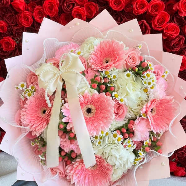 Pink and white bouquet with gerbera daisies, roses, and a ribbon bow