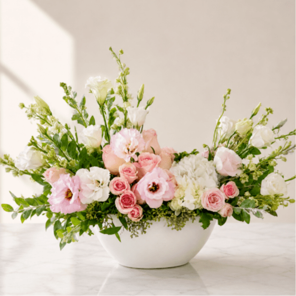 Pink and white floral arrangement in a white bowl vase