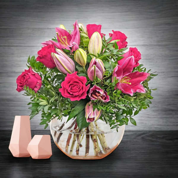 Pink roses and lilies arranged in a clear glass bowl vase