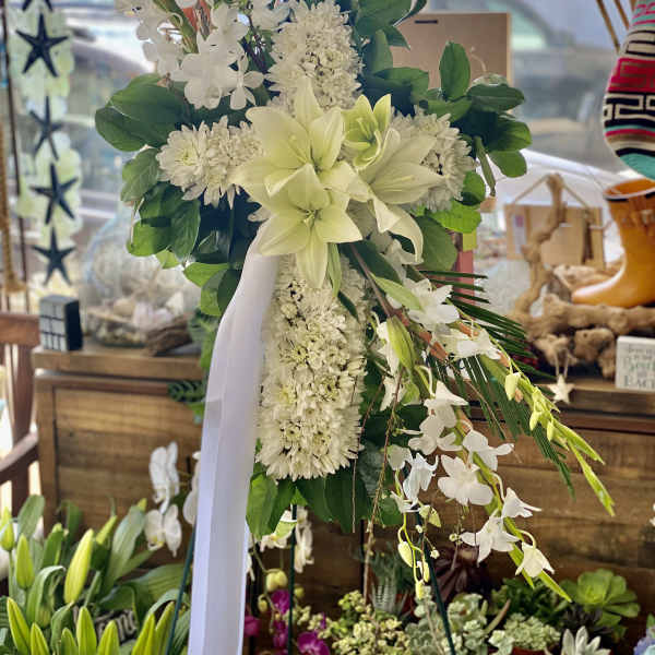 White floral standing spray with lilies and orchids on a ribboned easel