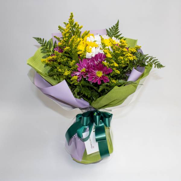 Bouquet of purple, white, and yellow flowers wrapped in lavender and green paper