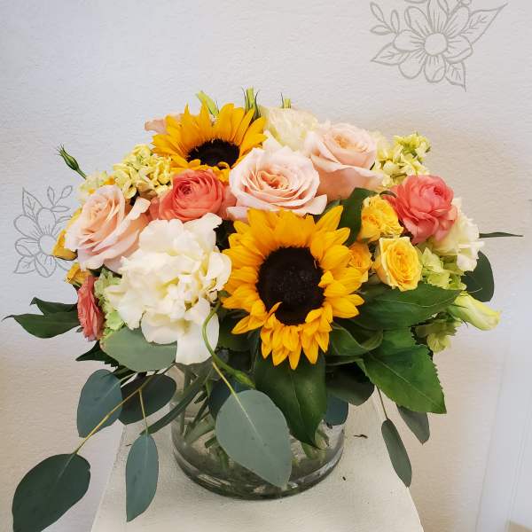 Bouquet of sunflowers, roses, and hydrangeas in a glass vase