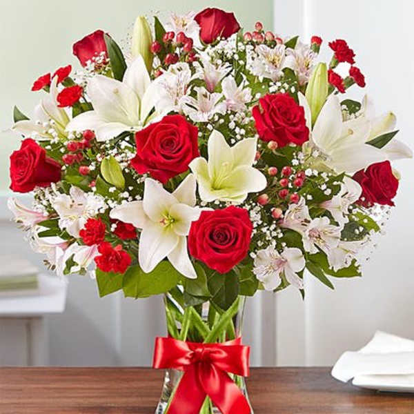 Bouquet of red roses and white lilies in a glass vase with a red ribbon