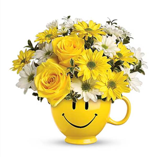 Yellow roses and daisies arranged in a smiley-face mug