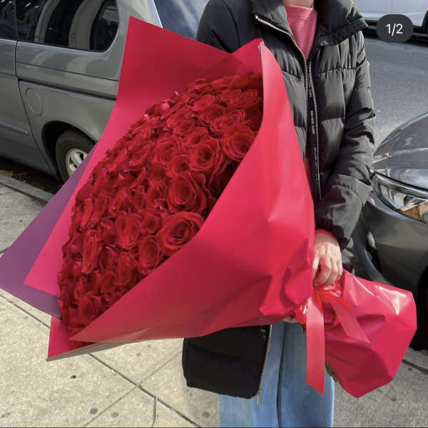 Large bouquet of red roses wrapped in bright pink paper