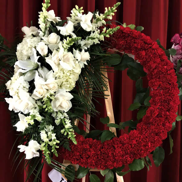 Large red and white floral wreath on a stand with a ribbon