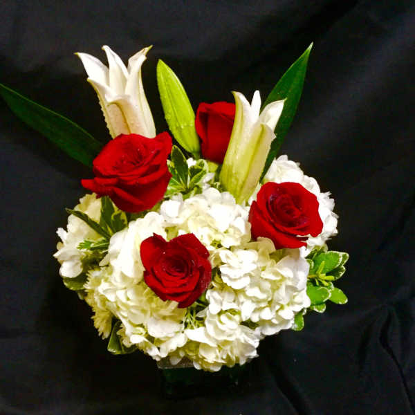 Red roses and white lilies in a compact arrangement with white hydrangeas