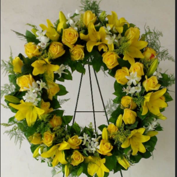 Yellow floral wreath with roses and lilies on a stand
