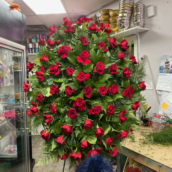 Large standing arrangement of red roses with greenery