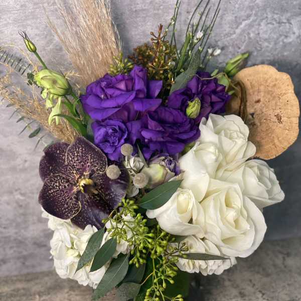 Purple and white floral arrangement with orchids in a vase