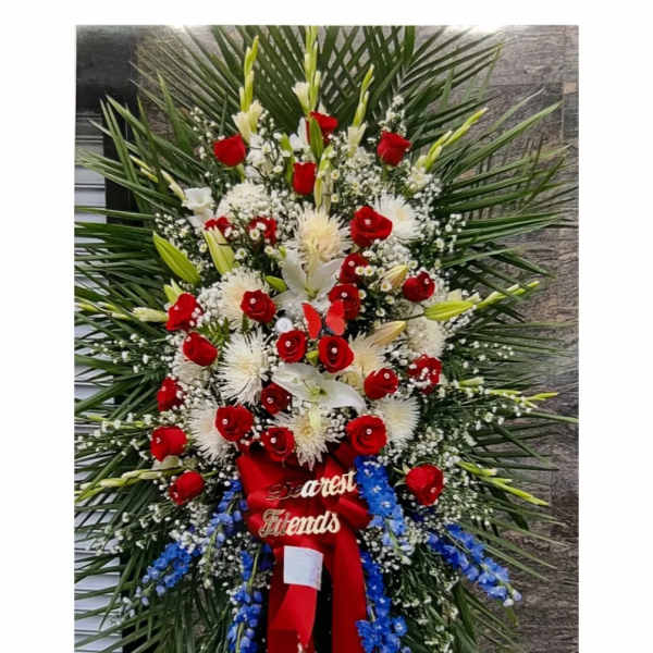 Large standing floral spray with red roses, white lilies, and blue accents