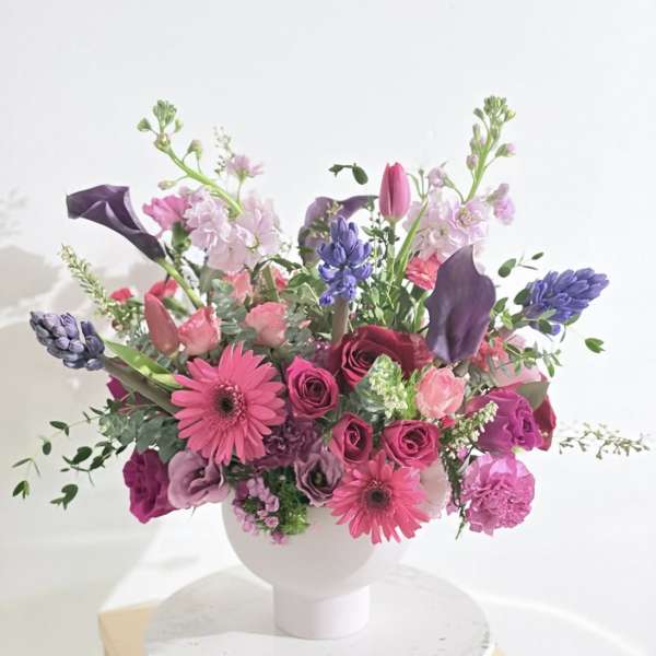 Pink and purple mixed bouquet in a white vase