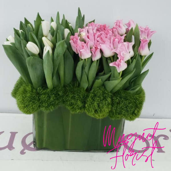 Pink and white tulips arranged in a rectangular glass vase