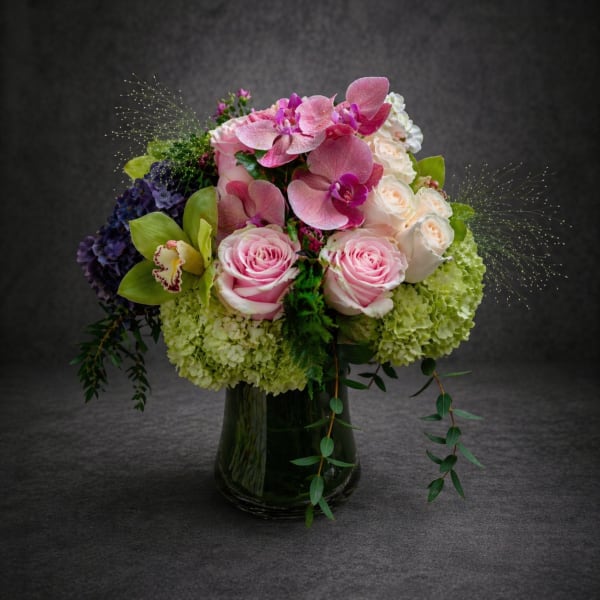 Pink and white floral arrangement in a dark glass vase