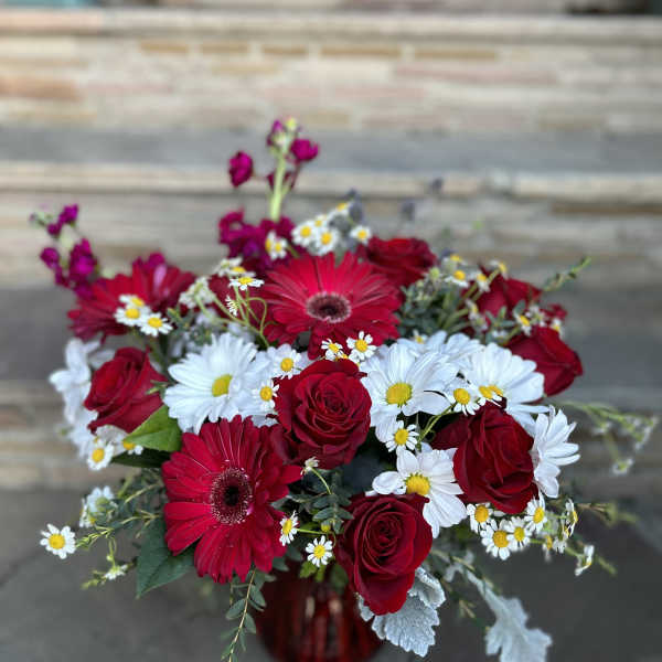 Red roses and gerbera daisies with white daisies in a red vase