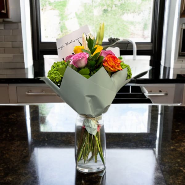 Bouquet of pink, yellow, and orange roses in a glass vase