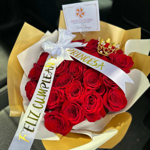 Bouquet of red roses wrapped in gold and white paper with a ribbon and crown topper