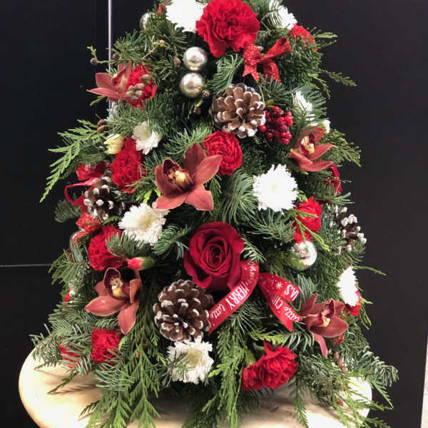 Christmas tree-shaped arrangement with red and white flowers and pinecones