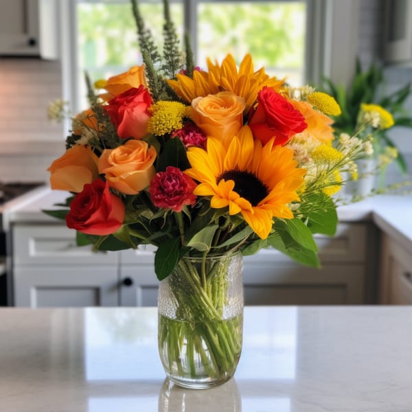 Bouquet of sunflowers, roses, and carnations in a glass vase