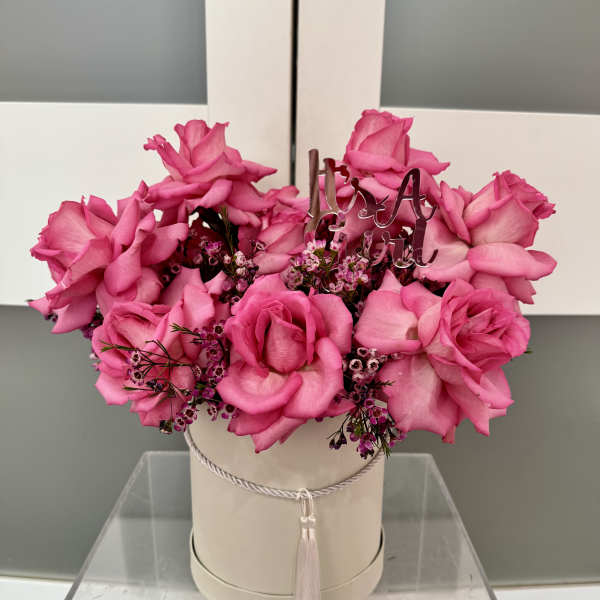 Pink rose arrangement in a round hat box with a tassel tie