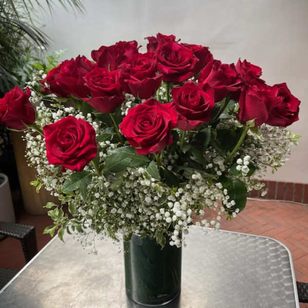 Bouquet of red roses with baby's breath in a dark glass vase