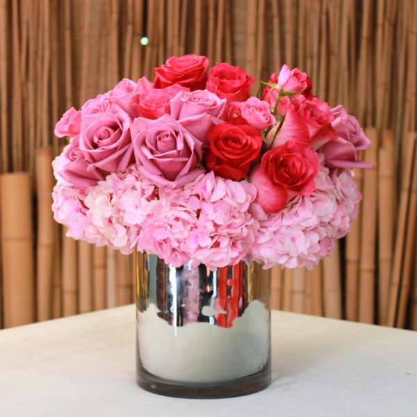 Pink and red roses arranged in a mirrored vase
