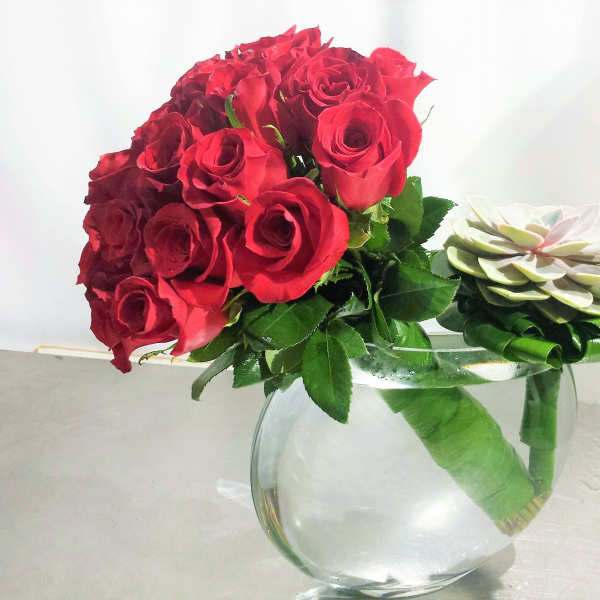 Red rose bouquet with a white succulent accent in a clear glass vase
