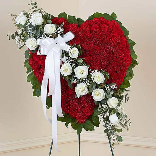 Heart-shaped red floral wreath with white roses and a white ribbon