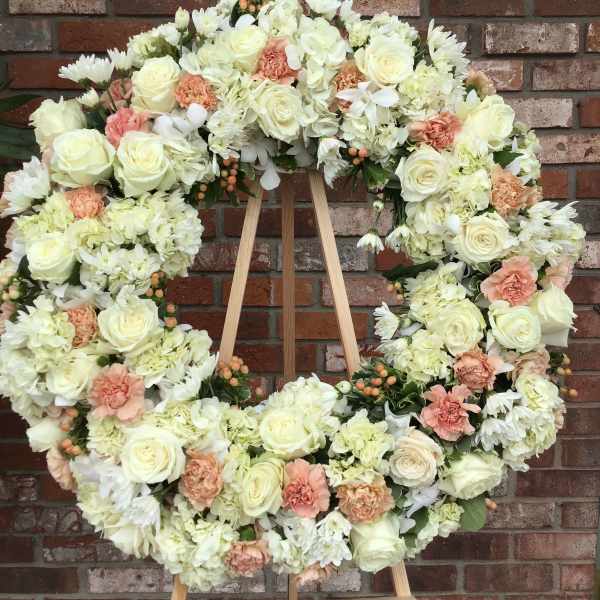 Large floral wreath of white and blush blooms on a wooden easel