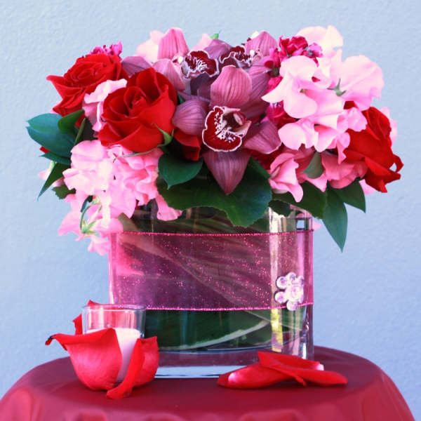 Bouquet of red roses and pink orchids in a glass vase