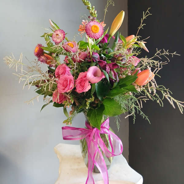 Pink and orange mixed bouquet in a glass vase with a ribbon