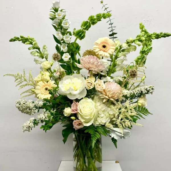 Tall mixed bouquet in a clear glass vase with white and pale pink flowers