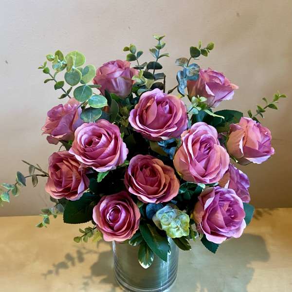 Pink roses arranged in a metal vase with eucalyptus