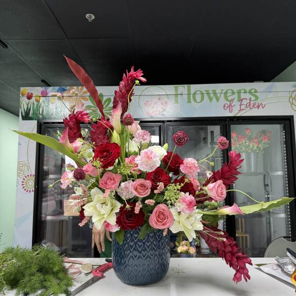 Large pink and red floral arrangement in a blue vase