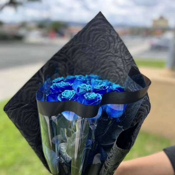 Bouquet of bright blue roses wrapped in black paper