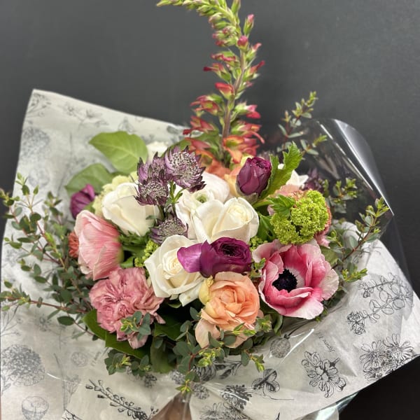 Mixed bouquet of pink, white, and peach flowers wrapped in printed paper