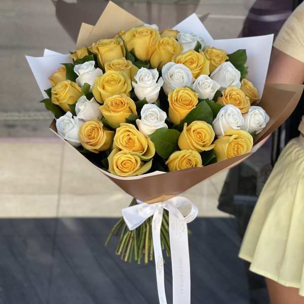 Bouquet of yellow and white roses wrapped in brown paper
