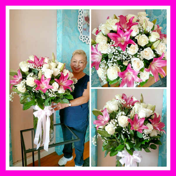 Large bouquet of pink lilies and white roses in a glass vase with a ribbon