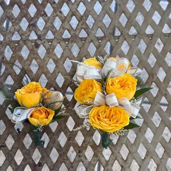 Two yellow rose boutonnieres with white ribbon bows