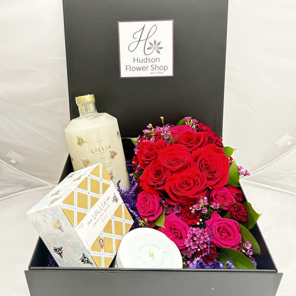 Boxed gift set with red roses, a bottle, and packaged bath items