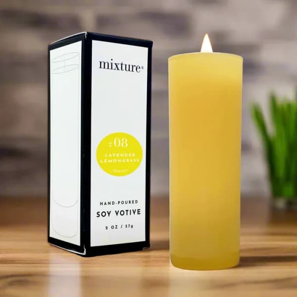 Yellow votive candle beside its box on a wooden surface