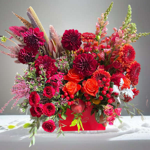 Vibrant red and orange floral arrangement in a red container