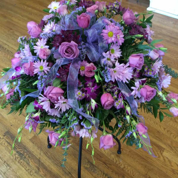 Pink and purple floral arrangement on a black stand with ribbon