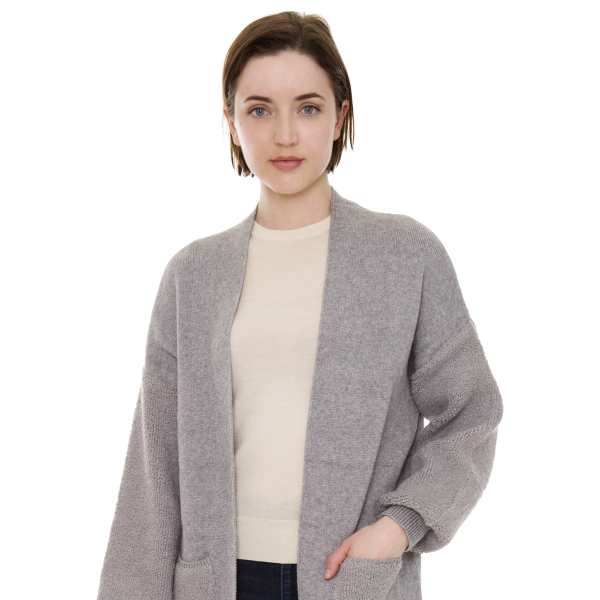 Woman wearing a long gray open-front cardigan over a light top and dark jeans